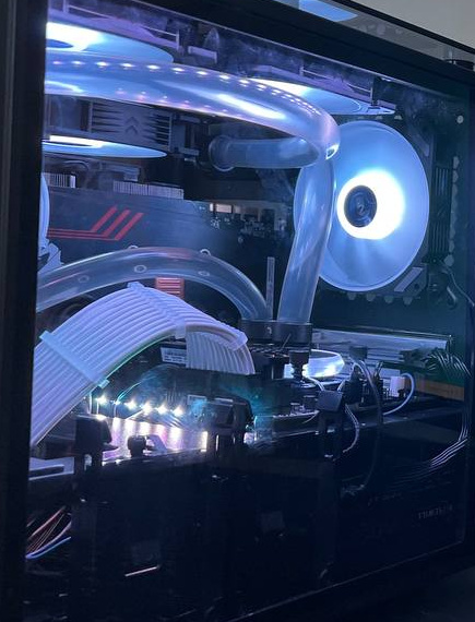PC interior with pale lighting, clear curved tubes, white sleeved cables and an illuminated water block