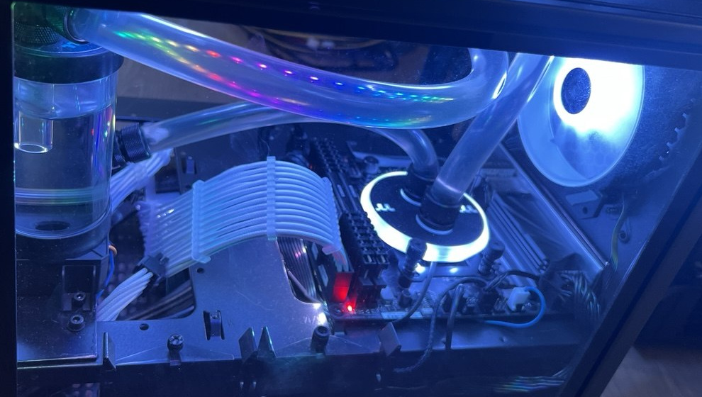 Elevated view of clear cooling tubes, reservoir and white sleeved cables