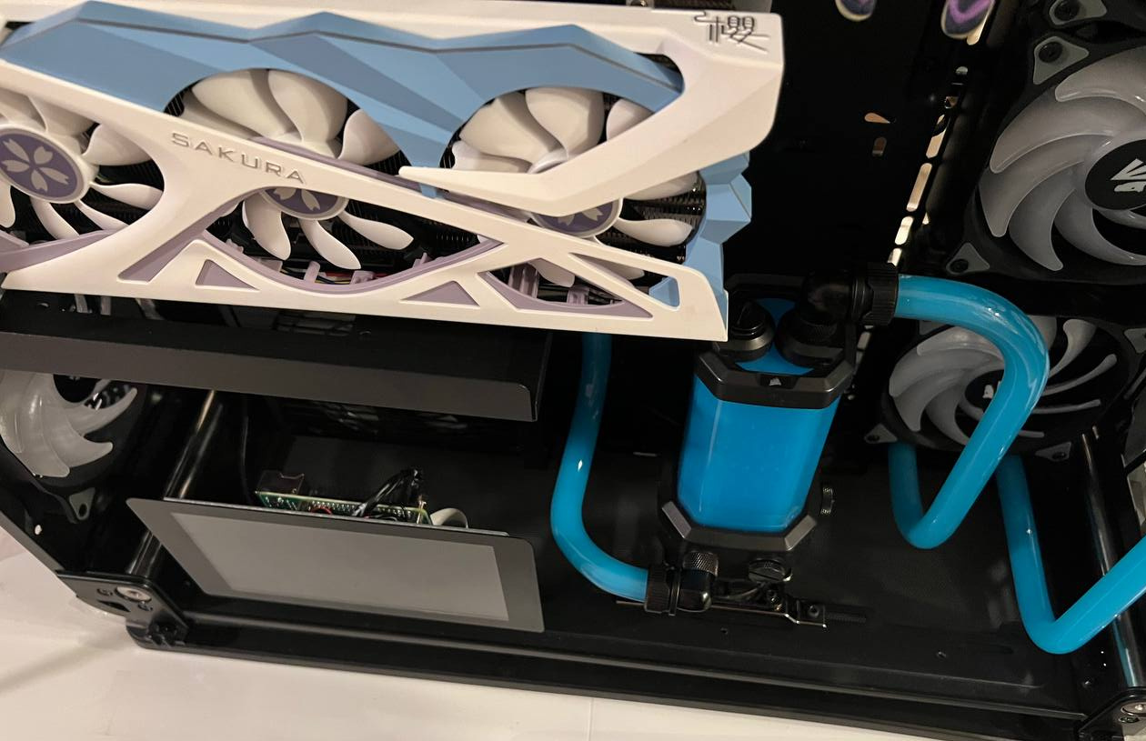 White fan-cooled graphics card above blue tubing and a reservoir
