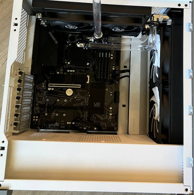Overhead view of an open white case with tubing and no installed graphics card