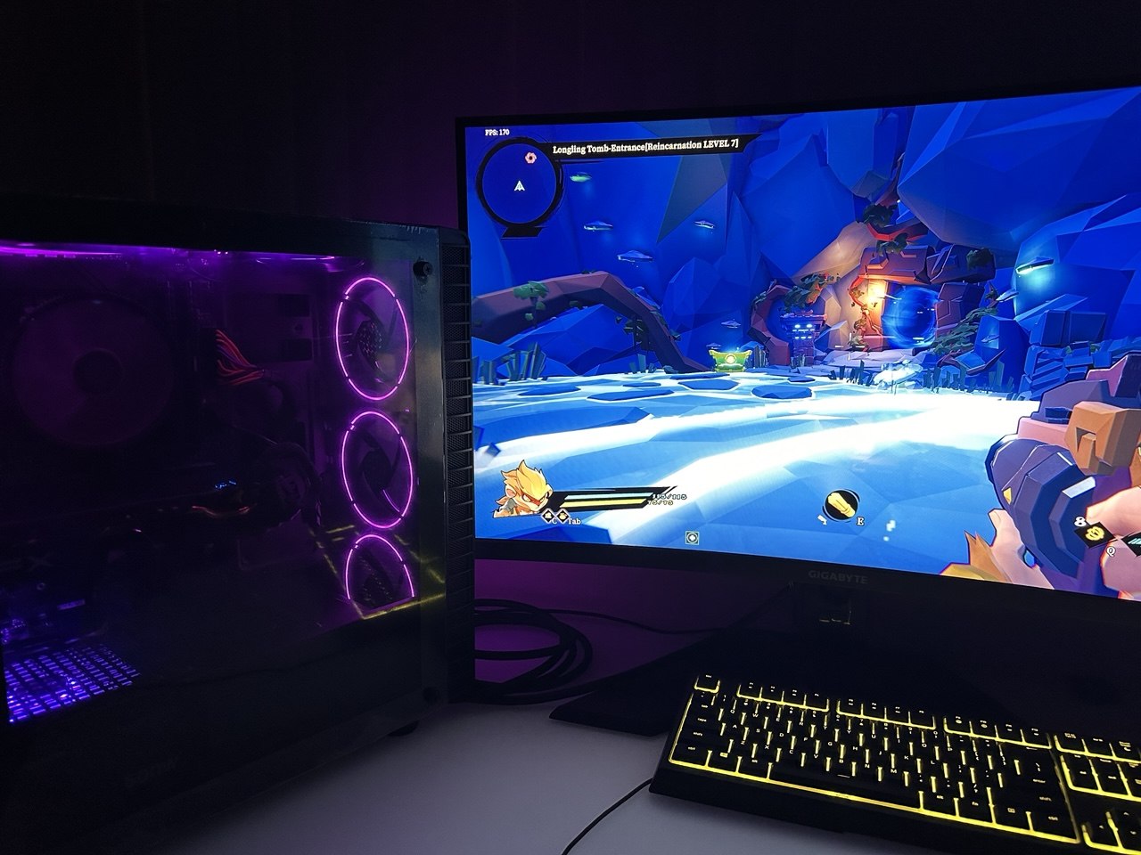 Purple-lit black PC beside a monitor showing a game and a keyboard