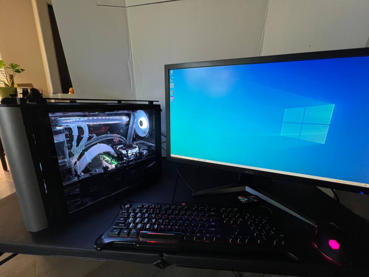 White-lit black PC with curved cooling tubes beside a monitor, keyboard and mouse