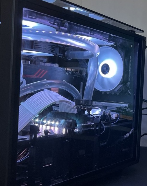 Black PC interior with white-lit fans, curved transparent cooling tubes and white sleeved cables